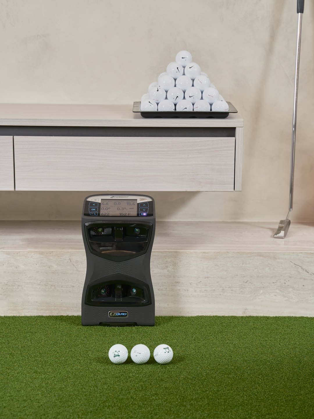 Golf balls and launch monitor on indoor artificial turf.